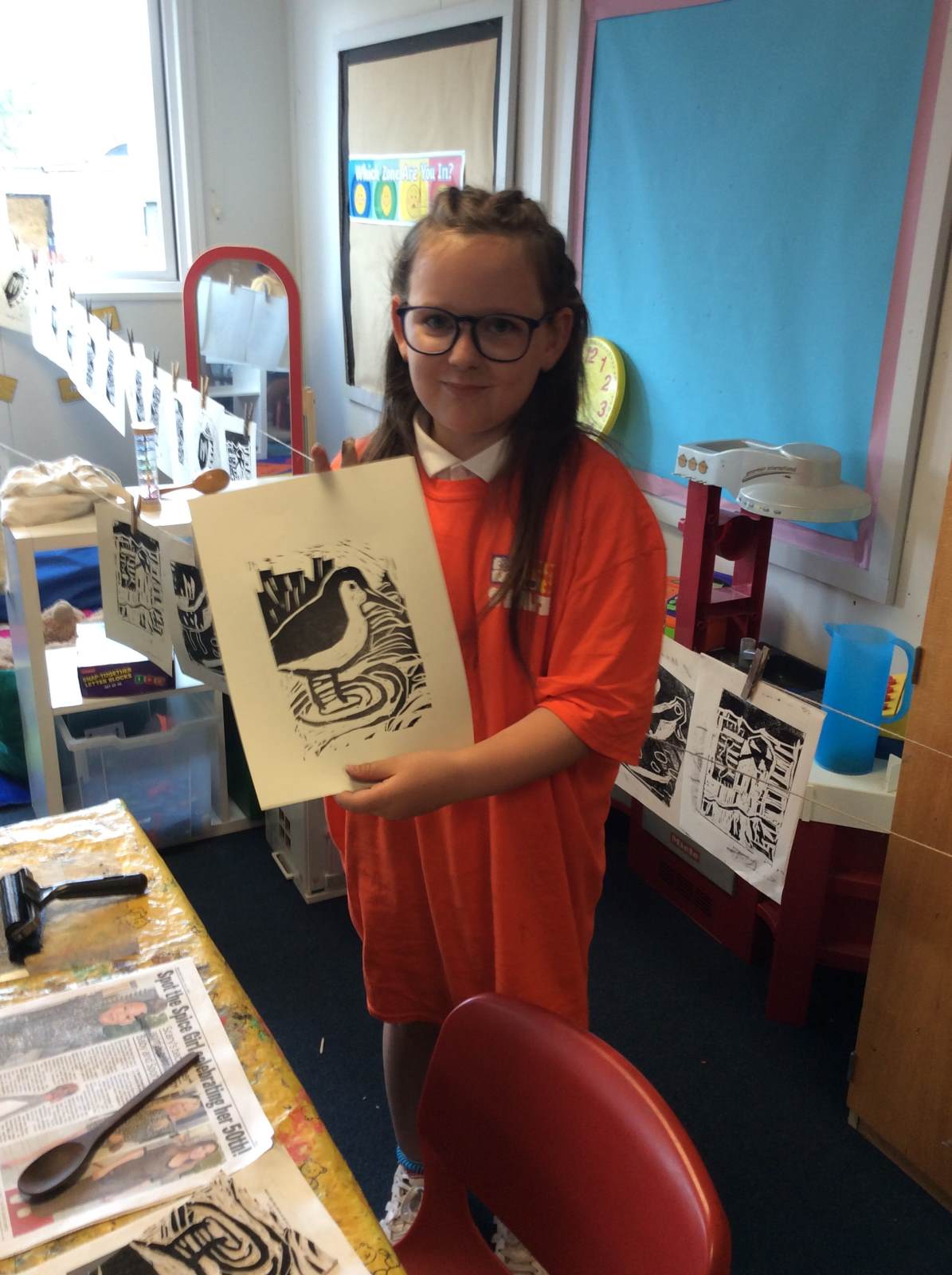 A girl holding a picture of a lino print of a sea bird. 